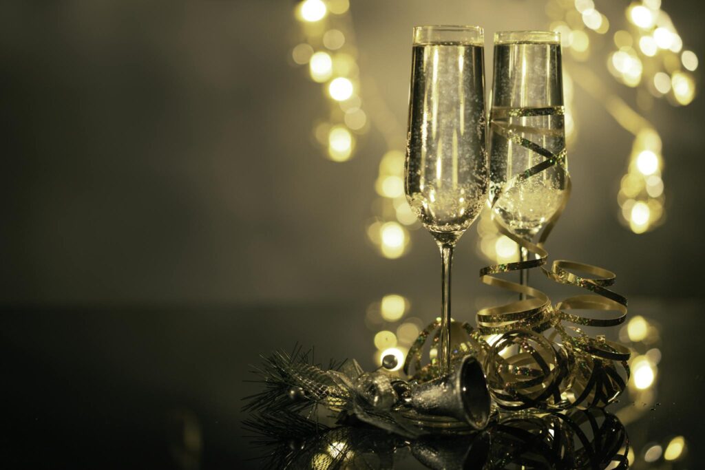 Detailný záber na dva poháre na flautu naplnené stužkami šumivého vína a vianočnou výzdobou
